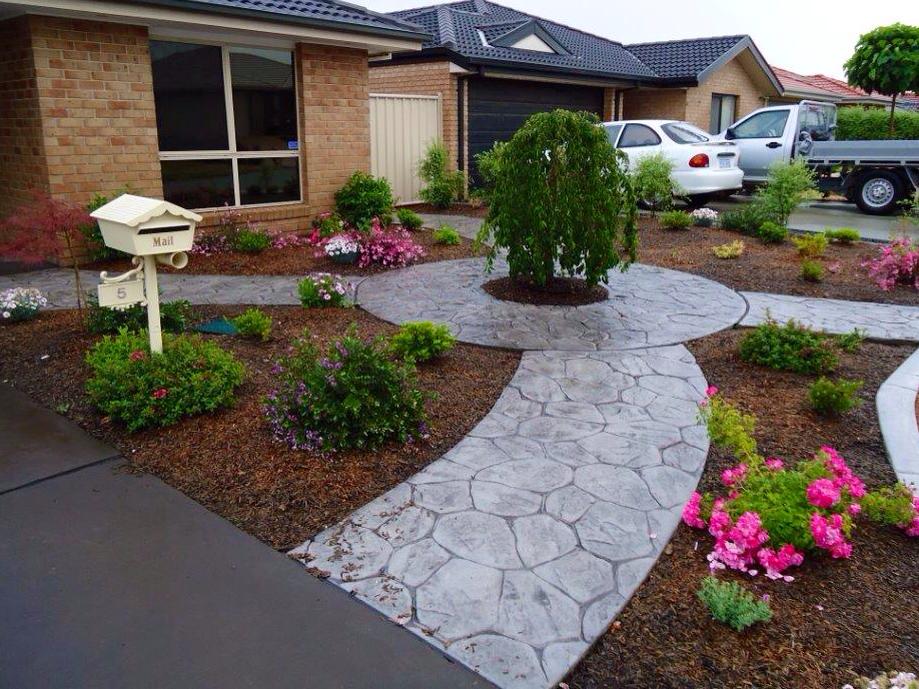 Curved paved garden with flowering plants and a feature tree